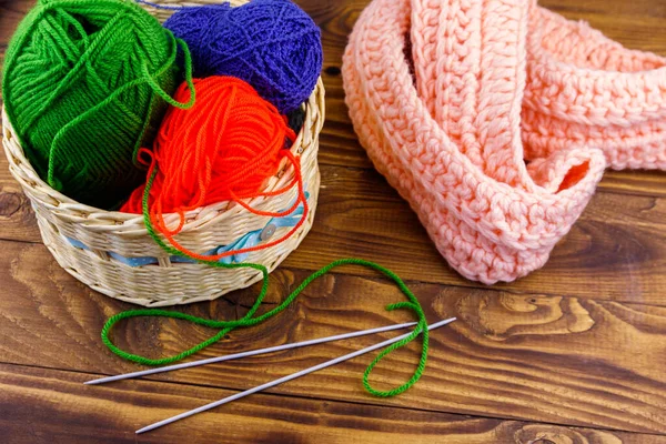 木制桌子上有色彩艳丽的针织针织针织围巾的柳条筐 — 图库照片