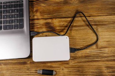 Harici HDD, tahta bir masadaki dizüstü bilgisayara ve USB flash diske bağlı. Üst Manzara. Veri depolama kavramı