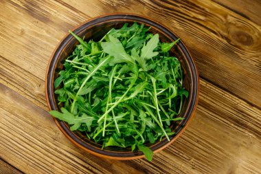 Tahta bir masada seramik kasede taze yeşil roka. Üst Manzara. Sağlıklı gıda veya vejetaryen konsepti