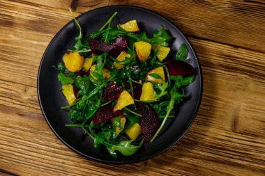Lezzetli roka salatası, pancar kökü ve portakallar ahşap masada. Üst Manzara. Sağlıklı gıda veya vejetaryen konsepti