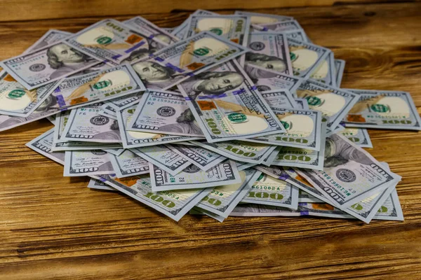 Heap of american one hundred dollar bills on a wooden desk