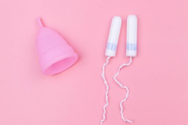 Pembe silikon regl kupası ve pembe arka planda tampon. Üst Manzara. Kadın hijyeni, jinekoloji ve sağlık kavramı