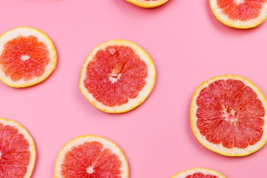 Pembe arka planda greyfurt dilimleri