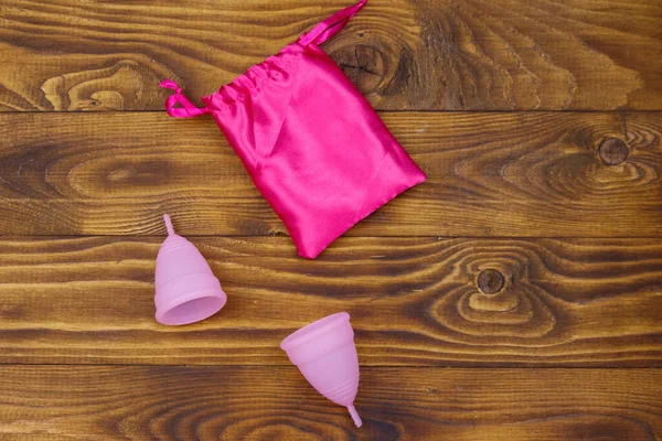 Zwei Rosa Wiederverwendbare Silikon Menstruationstassen Und Seidenbeutel Auf Holzgrund Ansicht — Stockfoto