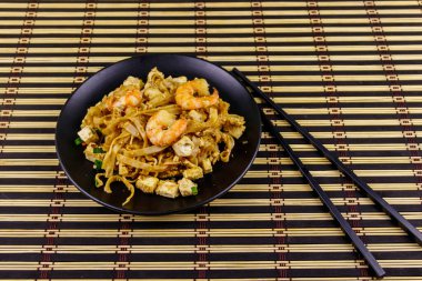 Tayland usulü kızarmış pirinç eriştesi, karides ve bambu hasırında soya peyniri. Tayland yemeği.