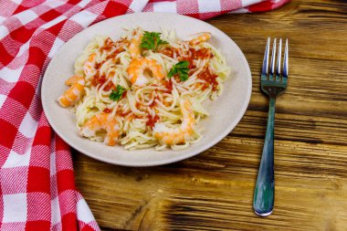 Karidesli makarna, domates sosu ve ahşap masada maydanoz.