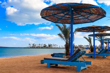 Tropik plajlarda güneş şemsiyeleri ve şezlonglar. Dinlenme, rahatlama, tatil, tatil