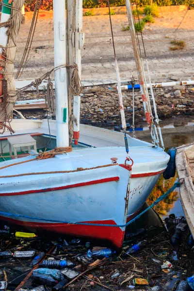 Old boats moored in dirty harbour. Pollution of river, sea, ocean water with waste, plastics garbage. Concept of pollution of ocean, sea and river coastline with plastic trash