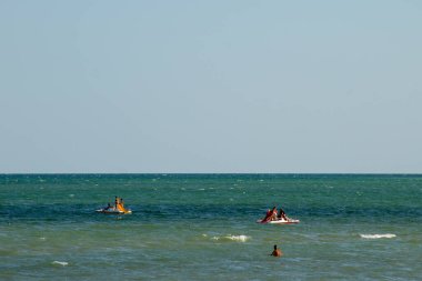 Genichesk, Ukrayna - 25 Ağustos 2017: İnsanlar pedallı tekneyle suda kayarak denize iniyor