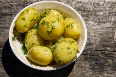Eski ahşap masada tereyağlı ve dereotlu haşlanmış yeni patates. Üst görünüm