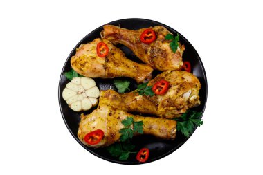 Beyaz arka planda izole edilmiş siyah bir tabakta baharatlı kızarmış tavuk budu. Üst görünüm