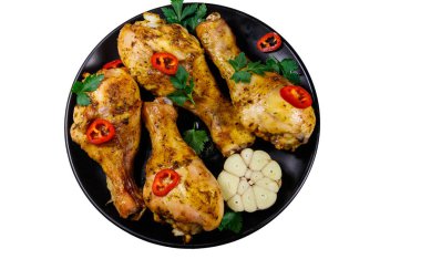 Beyaz arka planda izole edilmiş siyah bir tabakta baharatlı kızarmış tavuk budu. Üst görünüm