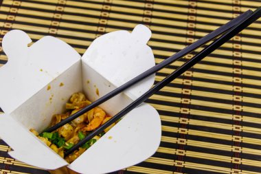 Kızarmış pirinç eriştesi, karidesli Pad Thai ve açık karton pakette tofu. Tayland mutfağı, yemek teslimatı.