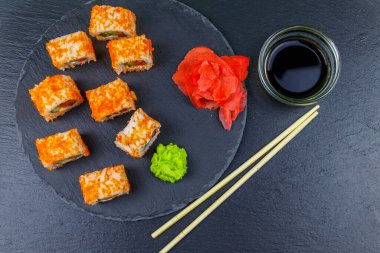 Suşi Philadelphia 'yı siyah bir levhada yuvarlıyor. Üst görünüm