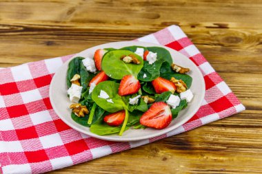 Tahta masada çilekli, ıspanaklı, cevizli ve peynirli taze sağlıklı salata.
