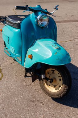 Şehrin caddesinde park etmiş mavi scooter.