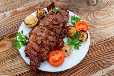 Izgara domuz etli soğan, domates ve maydanoz ahşap masa üzerinde beyaz plaka