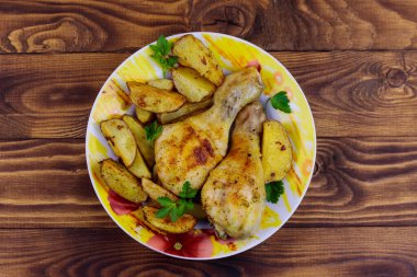 Ahşap masa üzerinde bir tabakta patates ile Fırında tavuk baget