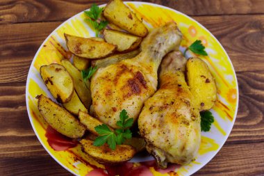 Ahşap masa üzerinde bir tabakta patates ile Fırında tavuk baget