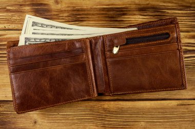 Ahşap masanın üzerinde Amerikan doları olan açık cüzdan. Üstte görüntü
