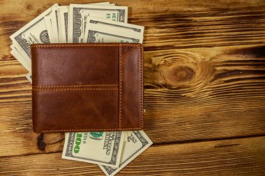 Kahverengi deri cüzdan ve ahşap masada Amerikan doları. Üst görünüm
