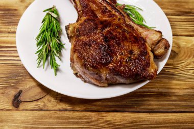 Biberiyeli biftek ve beyaz tabakta ahşap masa.