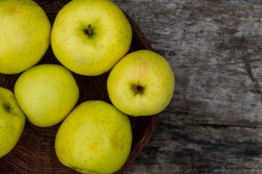 Rustik ahşap masa üzerinde bir sepet içinde olgun yeşil elma. Üstten görünüm