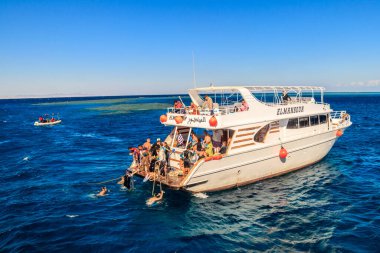Hurghada, Mısır - 7 Aralık 2018: Bilinmeyen insanlar mercan resiflerinde şnorkelle yüzüyor ve Kızıl Deniz 'deki yatlarda dinleniyorlar