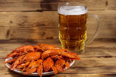 Haşlanmış kerevit ve bir kupa bira ahşap masada.