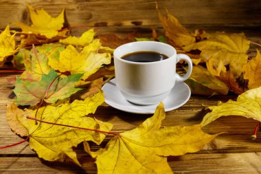 Bir fincan kahve ve sonbahar akçaağaç yaprakları ahşap masada. Sonbahar konsepti