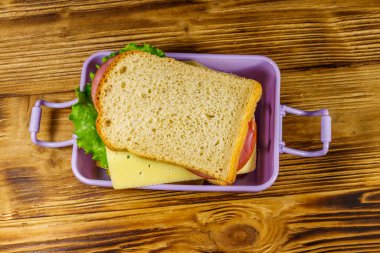 Tahta bir masanın üzerinde sandviçlerle beslenme çantası. Üst görünüm