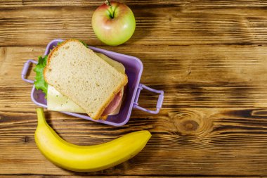 Sandviç, muz ve elmayla dolu bir beslenme çantası. Üst görünüm, alanı kopyala