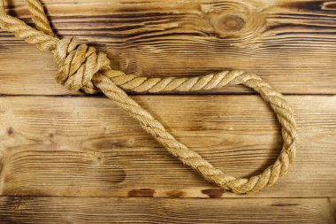 Ahşap arka planda ölümcül bir ip. İdam ya da intihar kavramı