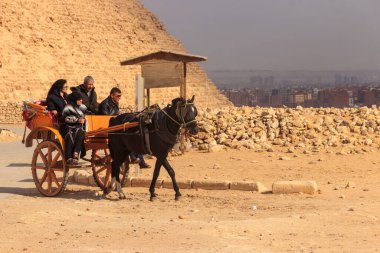 Kahire, Mısır - 8 Aralık 2018: Mısır 'ın Kahire kentinde Giza piramitleri yakınlarında at arabası süren turistler