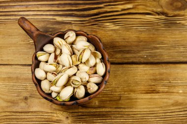 Ahşap bir masada seramik kasede fıstıklar. Üst görünüm
