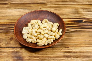 Ahşap bir masada çiğ fındıklı seramik tabak.