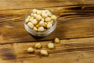 Ahşap masada cam kasede soyulmuş fındıklar.