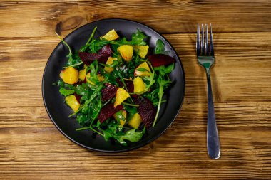 Lezzetli roka salatası, pancar kökü ve portakallar ahşap masada. Üst Manzara. Sağlıklı gıda veya vejetaryen konsepti