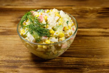 Yengeç çubuklu salata, mısır, salatalık, yumurta, pirinç ve mayonez ahşap masada.