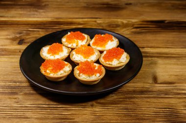 Kırmızı havyarlı turta ve ahşap bir masada yumuşak peynir.