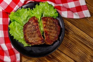 Ahşap masada marul yapraklı ızgara domuz bifteği. Üst görünüm
