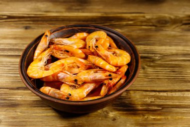 Tahta masadaki seramik kasede taze çiğ karidesler.