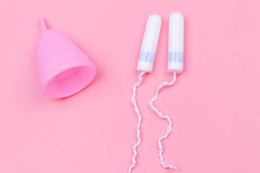 Pembe silikon regl kupası ve pembe arka planda tampon. Üst Manzara. Kadın hijyeni, jinekoloji ve sağlık kavramı
