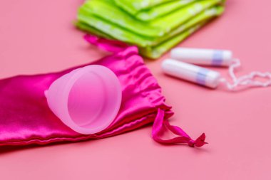 Pembe arka planda hijyenik ped, tampon ve regl kupası. Kritik günler, regl dönemi, kadın hijyeni