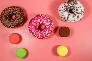 Pembe arka planda lezzetli çörekler ve kurabiyeler. Üst görünüm