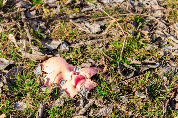 地面に葉の古い壊れた人形の顔 — ストック写真