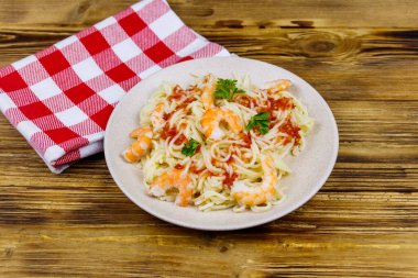 Karidesli makarna, domates sosu ve ahşap masada maydanoz.