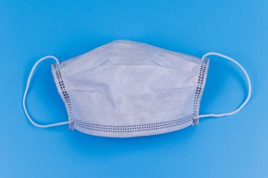 Mavi arka planda tek kullanımlık koruyucu tıbbi maske. Üst görünüm