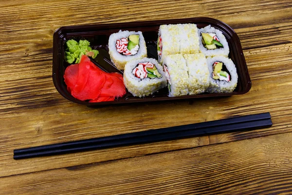 Rollos Sushi Uramaki Con Surimi Caja Plástico Sobre Mesa Madera —  Fotos de Stock
