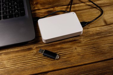 Harici HDD, tahta bir masadaki dizüstü bilgisayara ve USB flash diske bağlı. Veri depolama kavramı